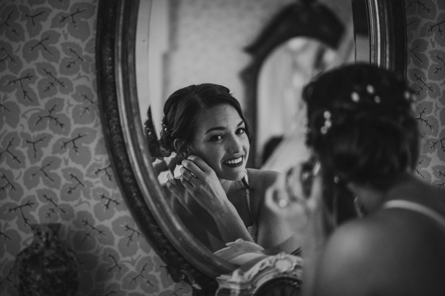 black and white mirror reflection of bride putting on earrings at The Kelton House Wedding