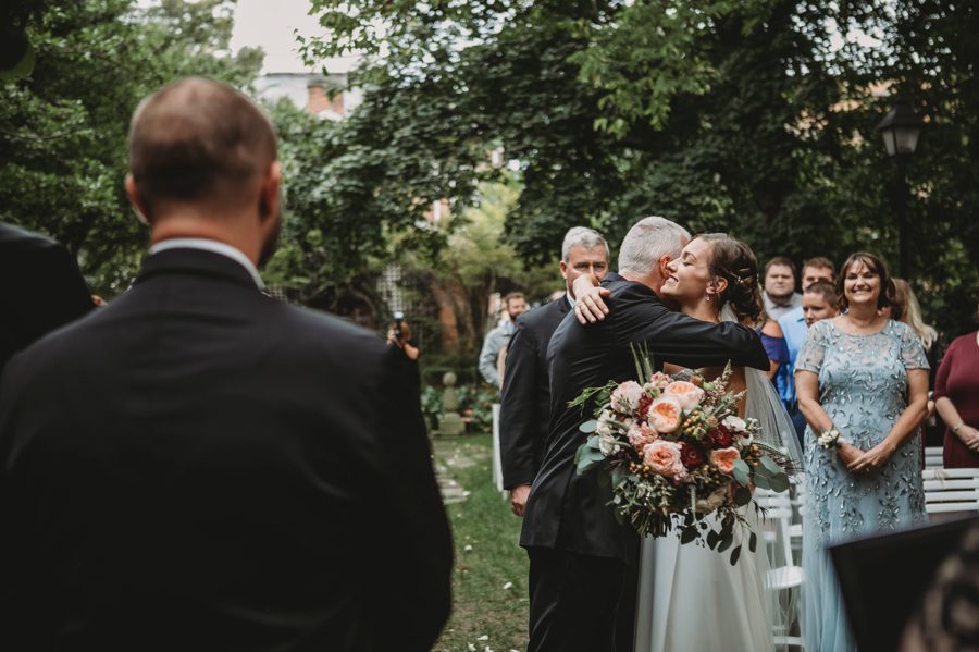 bride hugging father at end of wedding aisle