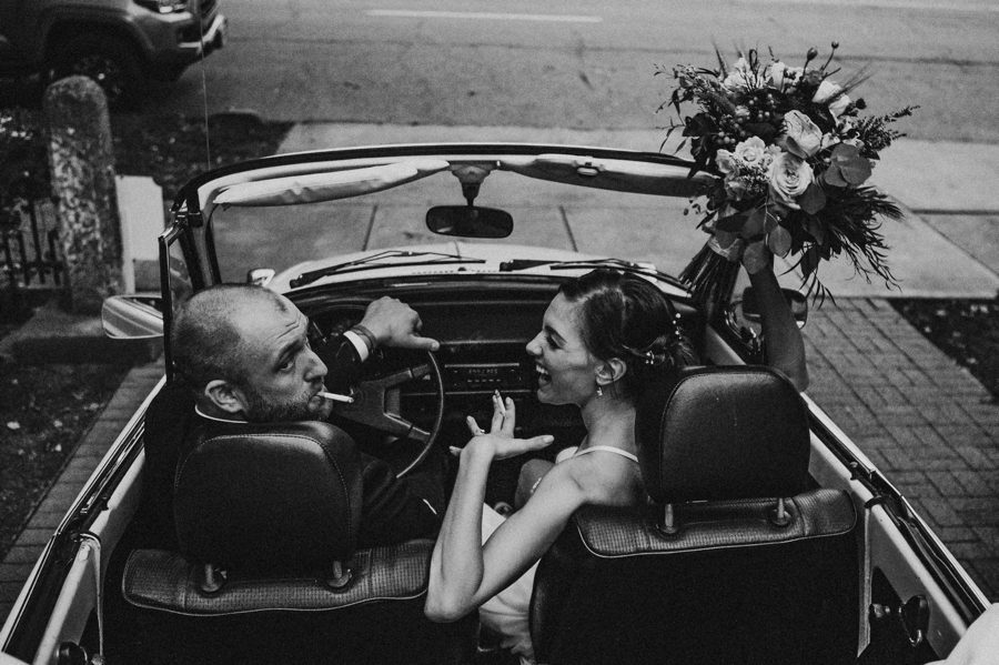 bride and groom smoking in vintage Volkswagen Beetle