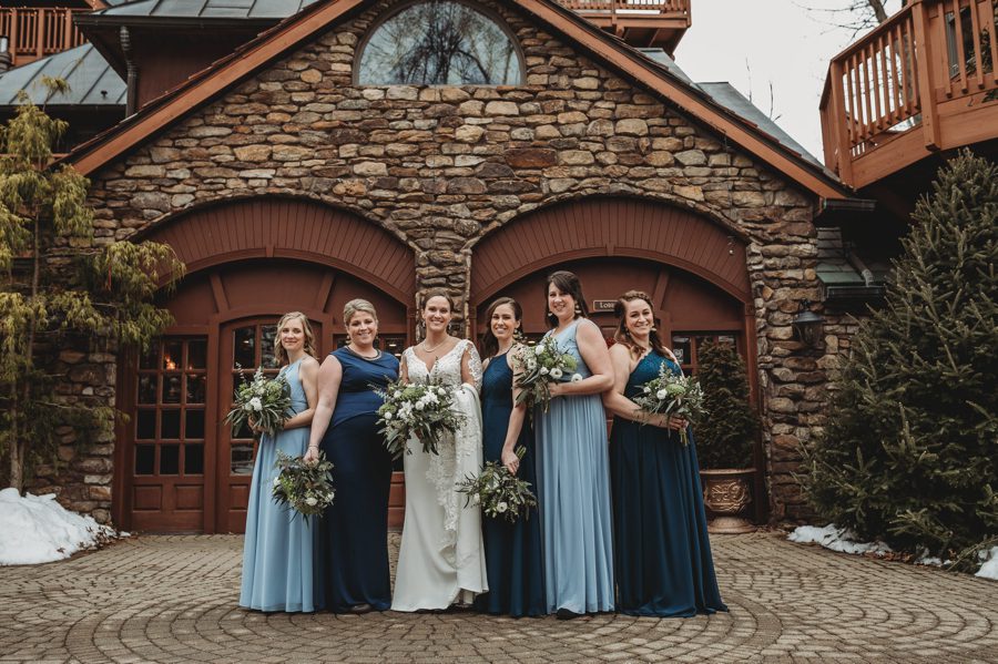 bride with bridesmaids against stone building
