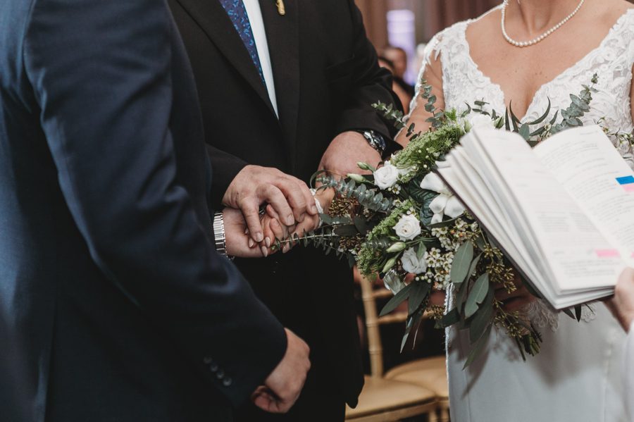 close up image of bride and groom holding hands