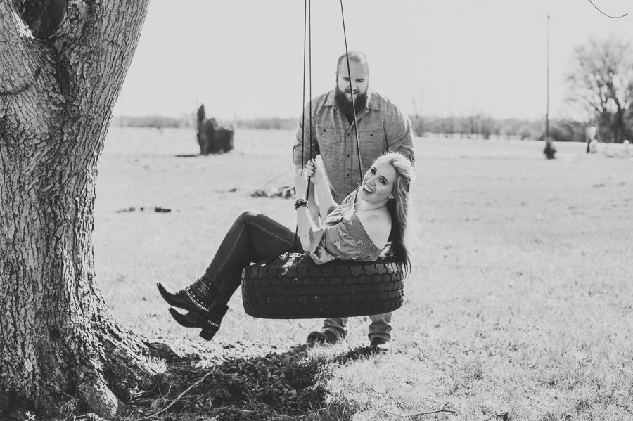 black and white image of man pushing fiancé on tire swing at Mt. Sterling Ohio Engagement Photos