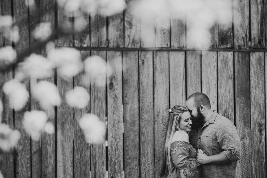 black and white image of man and woman cuddling next to barn at Mt. Sterling Ohio Engagement Photos