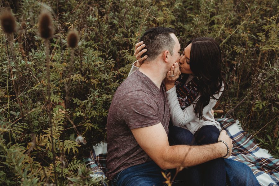 engaged couple kissing white sitting on plaid blanket at Newark Ohio Engagement Photos