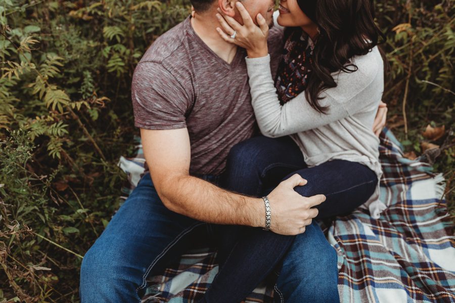 couple snuggled on plaid blanket for engagement session