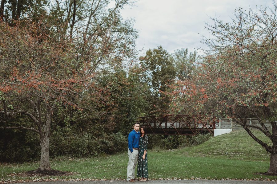 wide photo with engaged couple between two crab apple trees