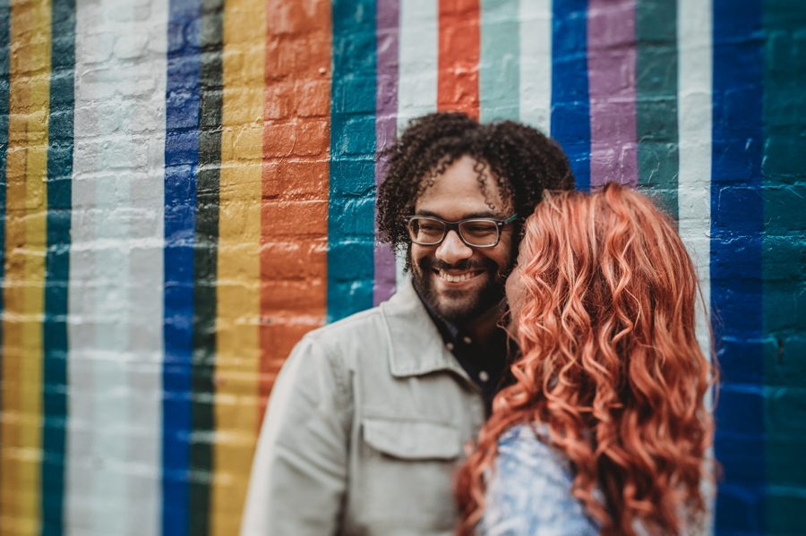 woman kissing fiancé on cheek in front of striped wall in the short north Columbus