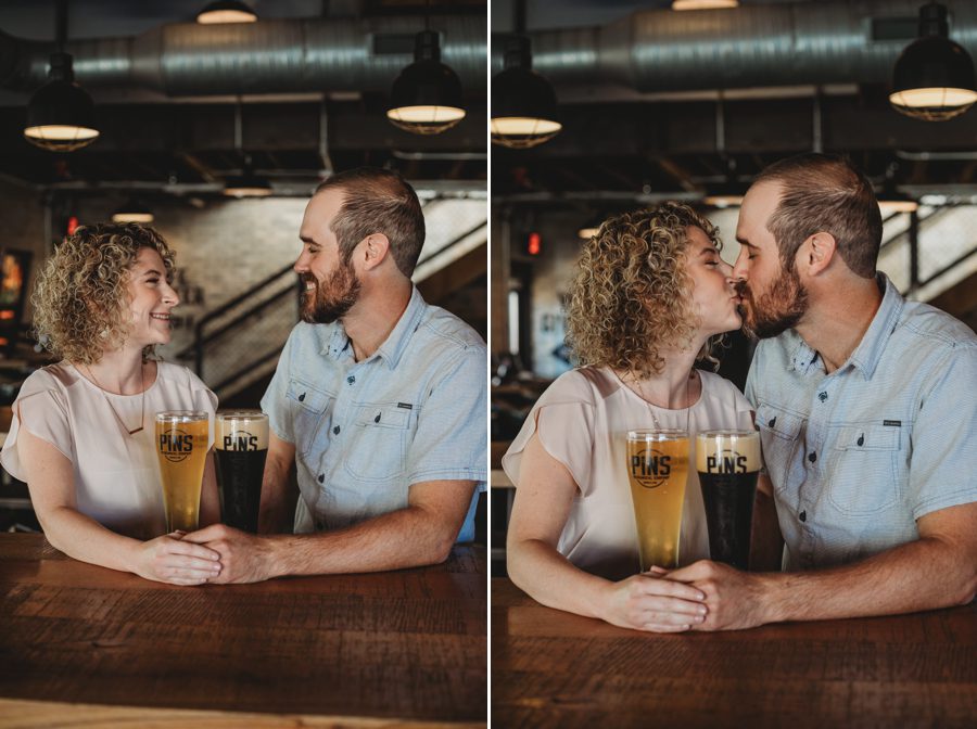 engaged couple sitting having beer and kissing at Pins Mechanical Engagement