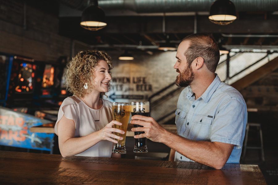 engaged couple cheering their beer glasses together