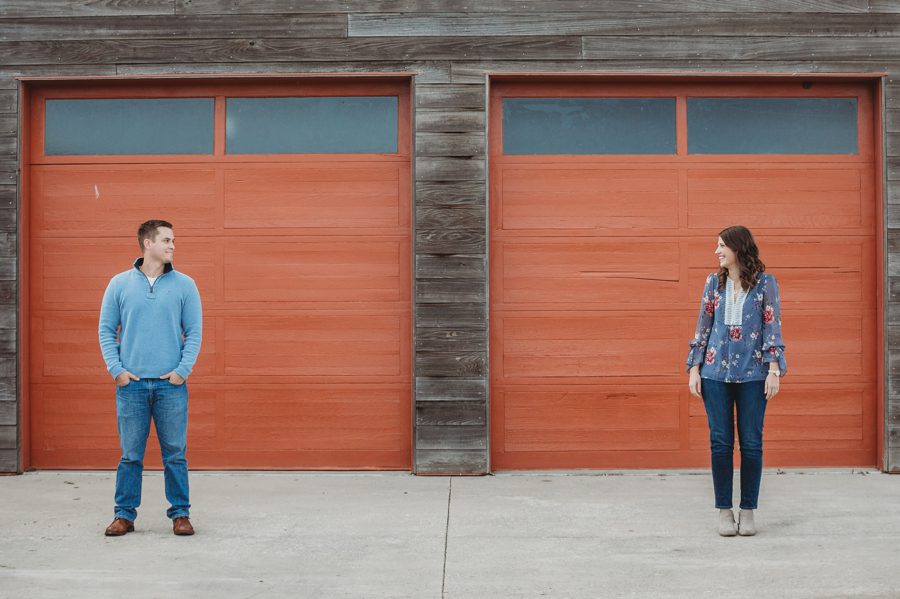 engaged couple looking at each other in front of orange garage doors