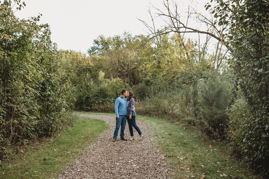 wide image of couple kissing while on a walking trail