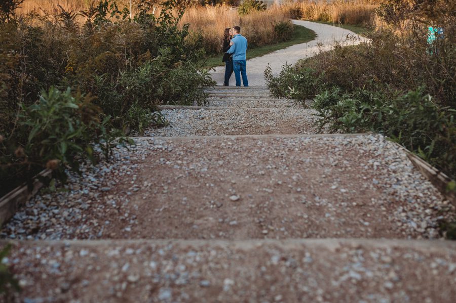 engaged couple kissing at end of gravel steps