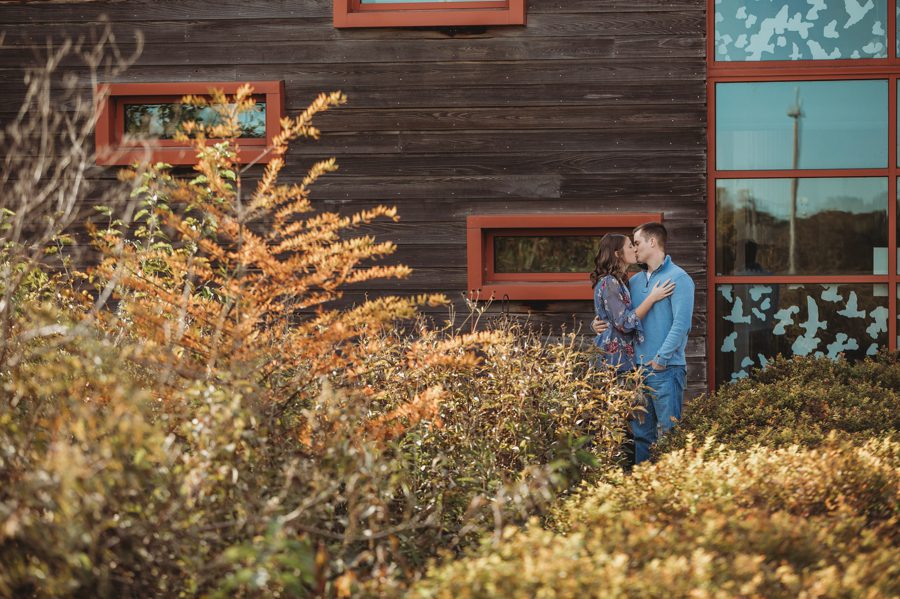 engaged couple kissing by building at Scioto Audubon Metro Park