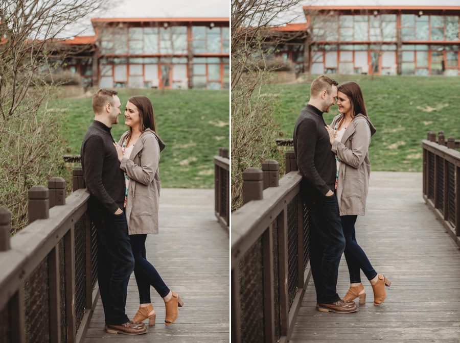 engaged couple with foreheads together while leaning on brown fence at Scioto Audubon Photos