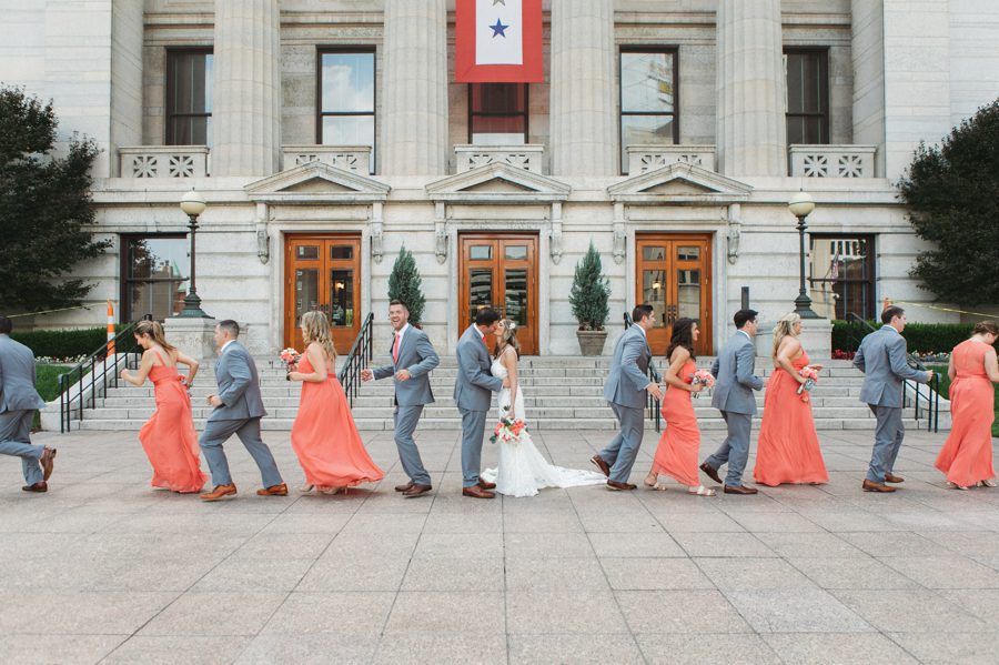 bride and groom kissing and wedding party running
