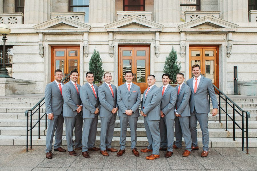 groom and groomsmen in grey suits with sunset color tie