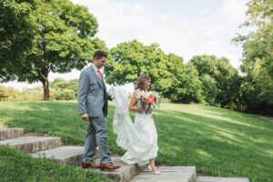 groom holding wedding dress train of brides wedding dress