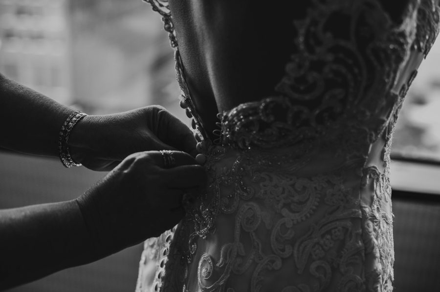 black and white photo of mother of bride buttoning wedding dress
