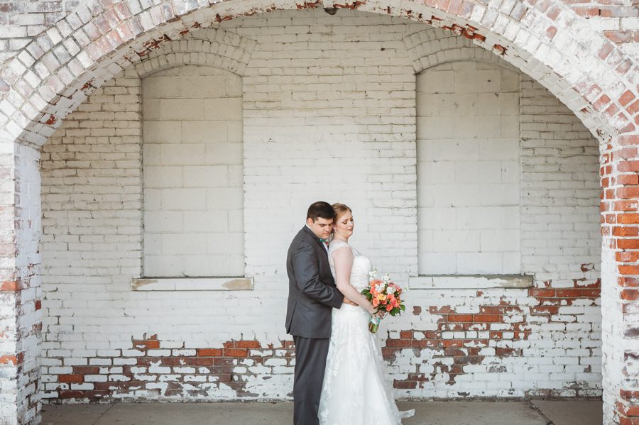 bride and groom hugging on white washed brick at Tiffany Blue Wedding in Columbus Ohio