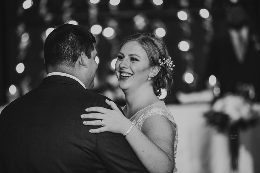 black and white image of bride smiling at groom during first dance