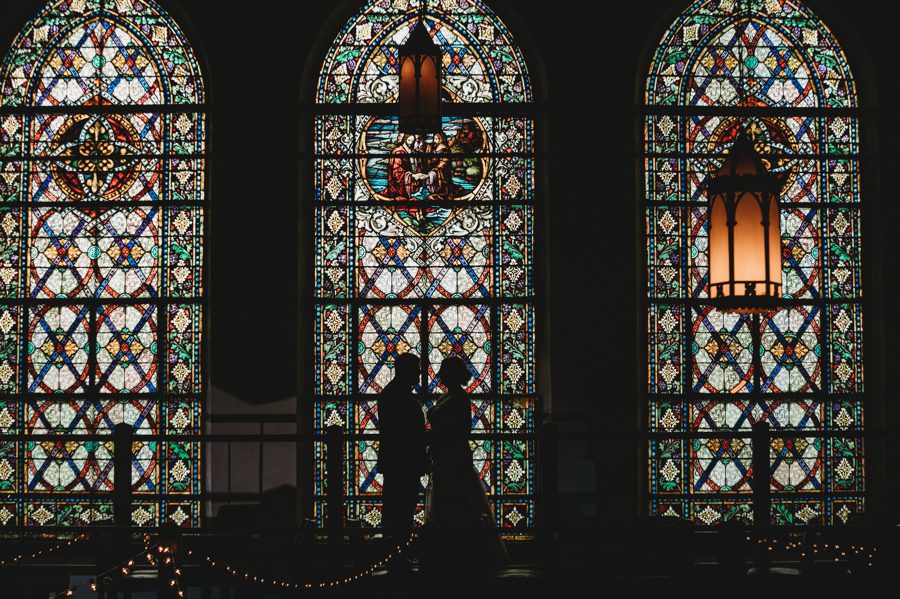 bride and groom in front of large stained glass windows at Tiffany Blue Wedding in Columbus Ohio The Bluestone