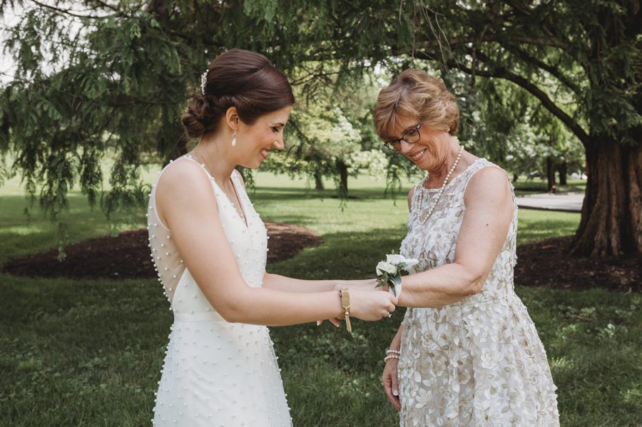 Candid capture by Forget Me Knot Photography of Kelsey placing corsage on her mothers wrist at Columbus, Ohio Darby House