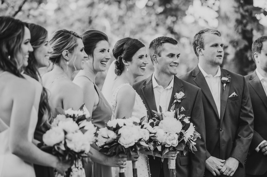Black and white candid side view of married couple with their wedding party