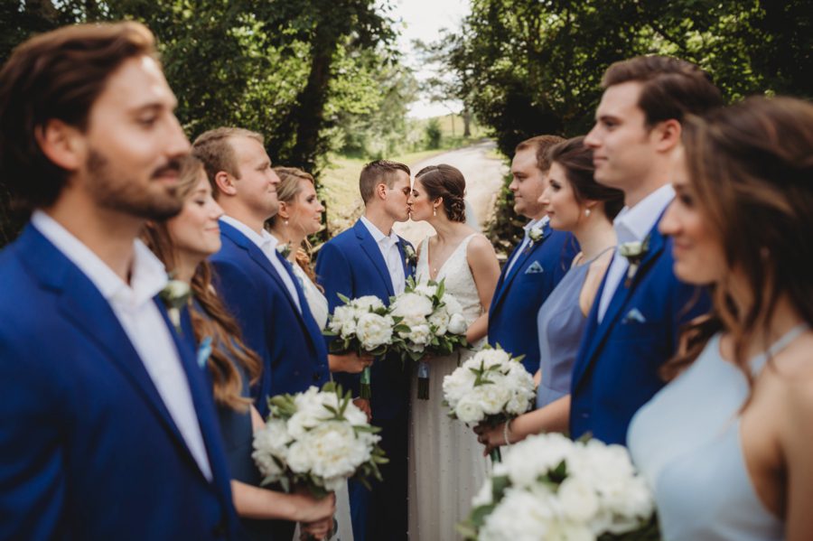 Unique capture of Kelsey and Jon kissing and their wedding party facing each other