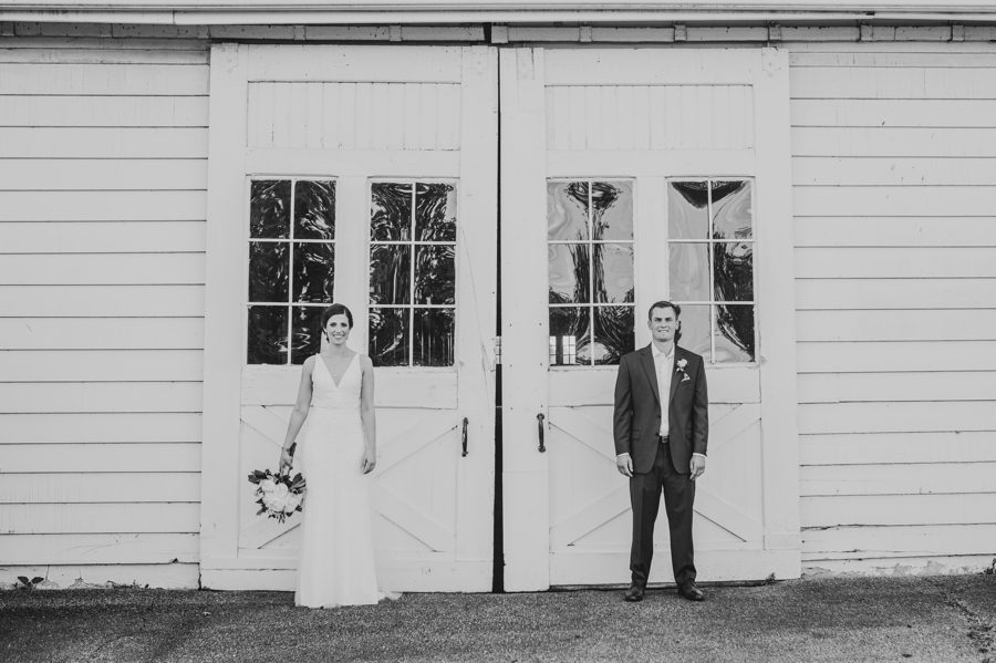 Black and white capture of Kelsey and Jon in front of white barn at Columbus, Ohio Darby House