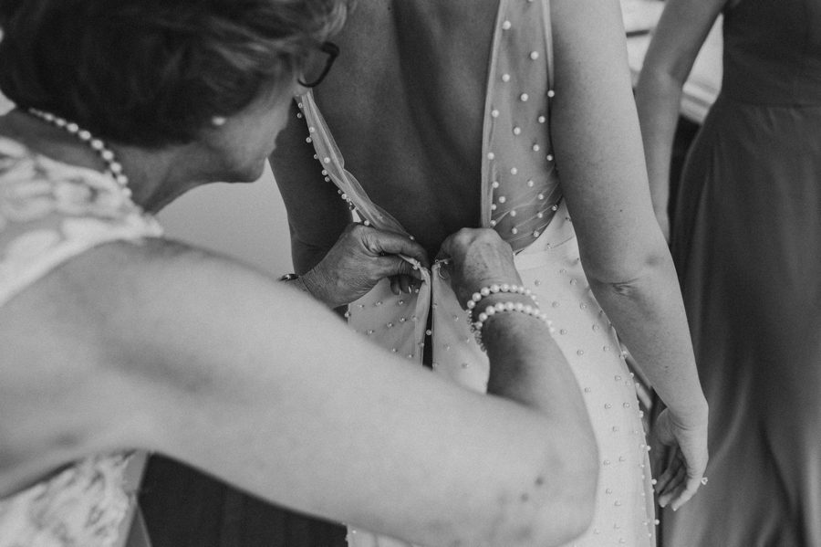Black and white capture of Kelsey's dress getting fastened
