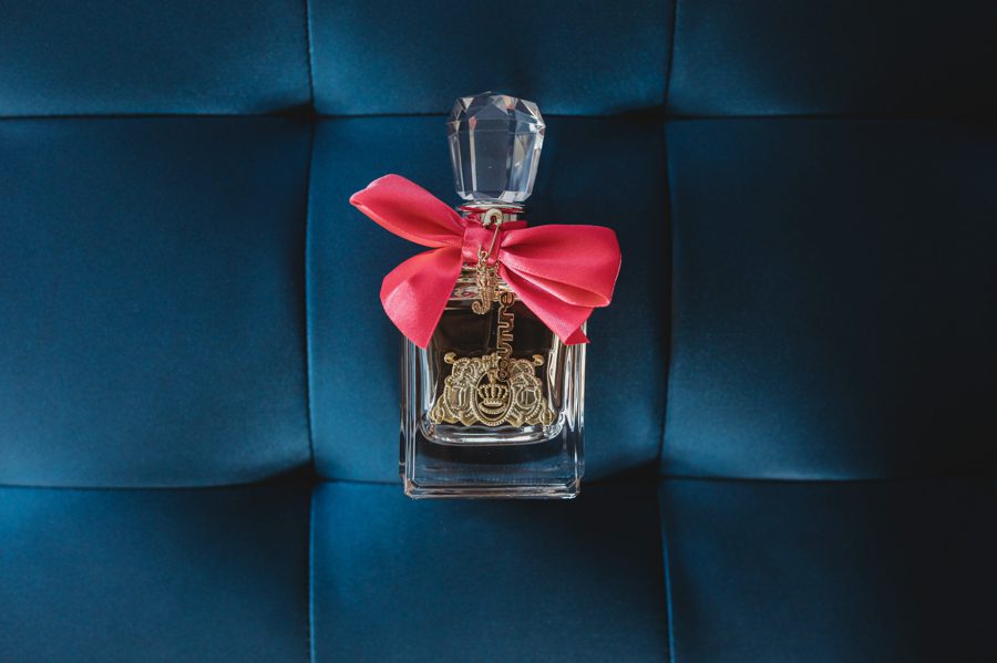 Juicy Couture perfume bottle with pink ribbon on blue ottoman