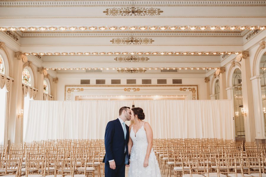 Emilee and Michael leaning into a kiss while standing next to each other in The Westin Ballroom