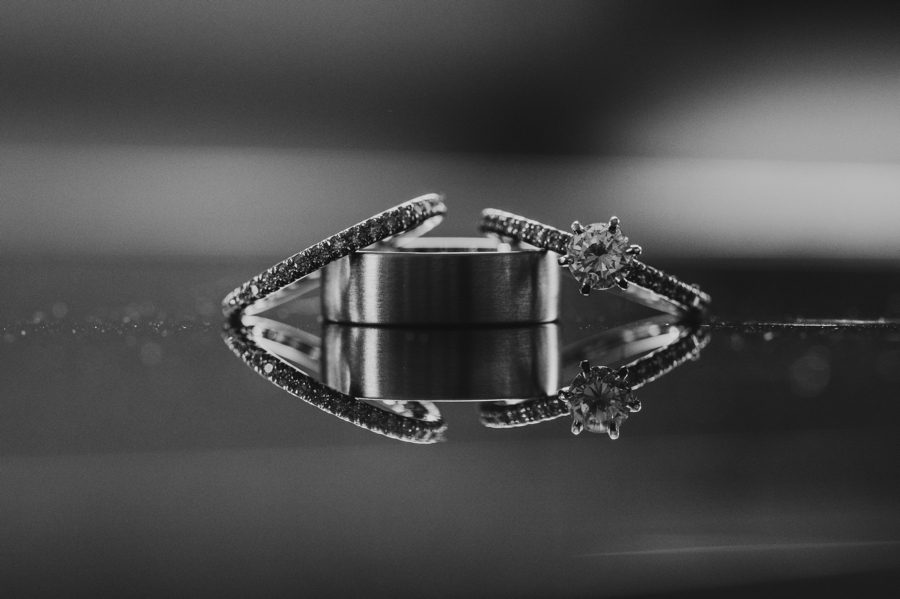 husband and wife wedding bands in black and white reflecting on glass