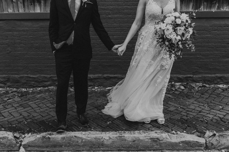 Black and white image of wedding couple holding hands