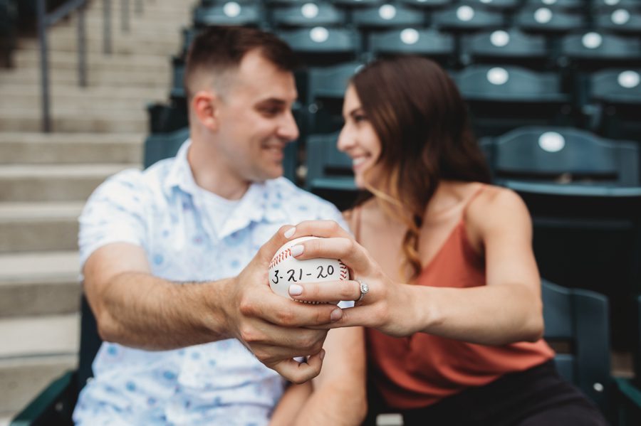engaged couple holding baseball with wedding date