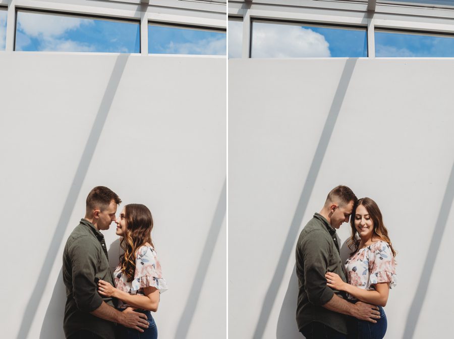 engaged couple looking at each other on white wall with shadow lighting