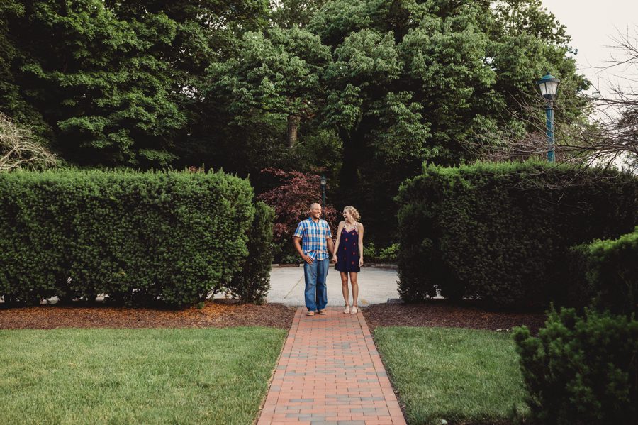 Wide angle of Rachel and Sean standing between hedges for their Jeffrey Mansion Engagement Photos