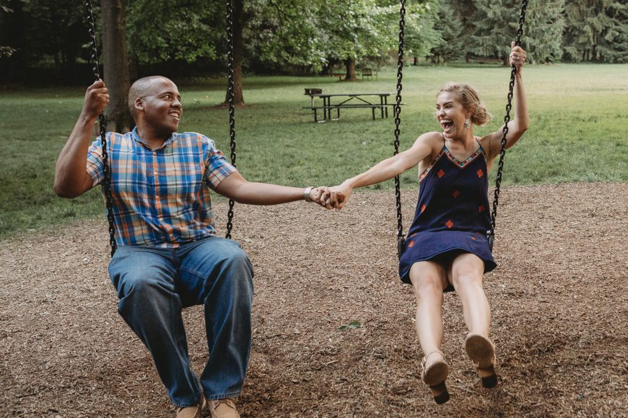 Rachel and Sean holding hands while swinging on a swing set at Jeffrey Mansion