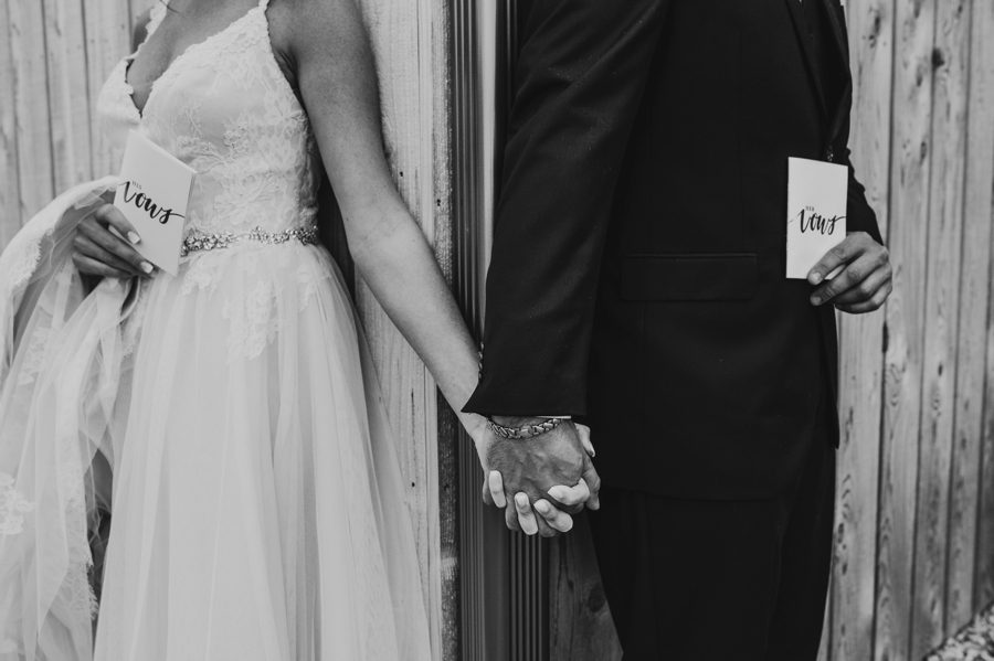 black and white capture of Cortni and Darren holding hands with their vow books at Rusty River Barn