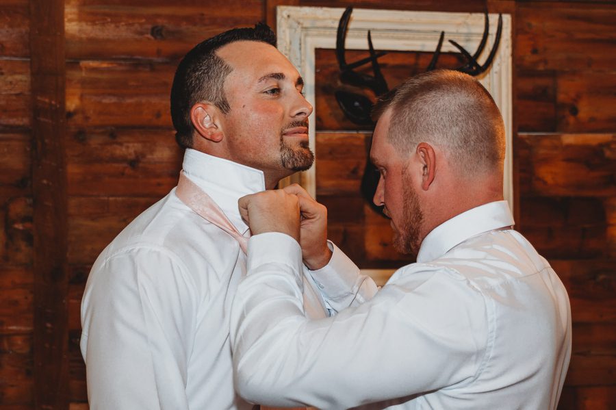 Darren having his tie adjusted by a groomsmen in the grooms suite
