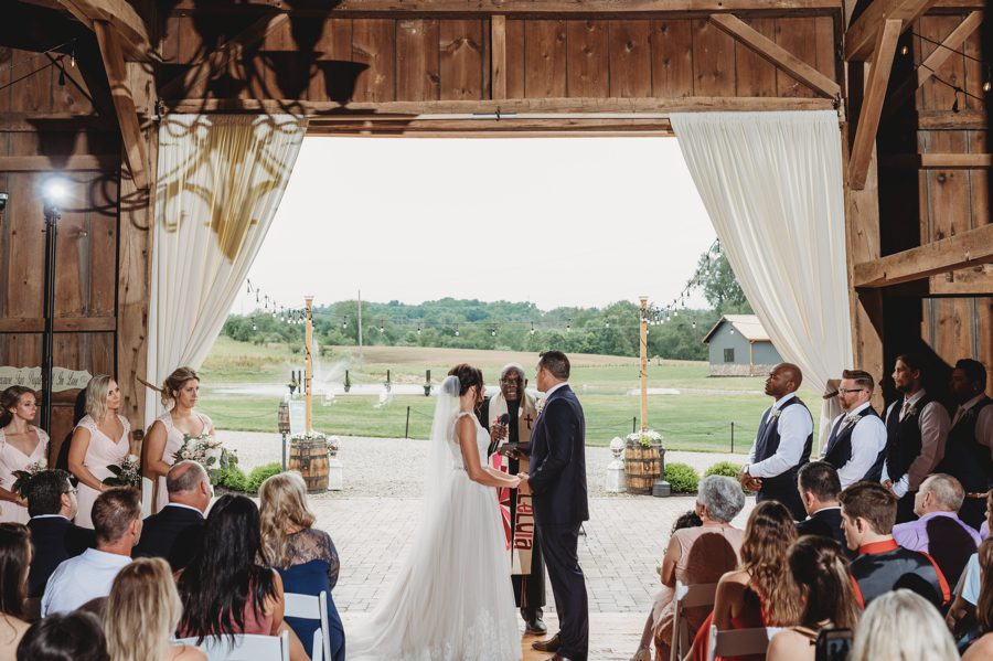 Cortni and Darren exchanging vows inside the Rusty River Barn