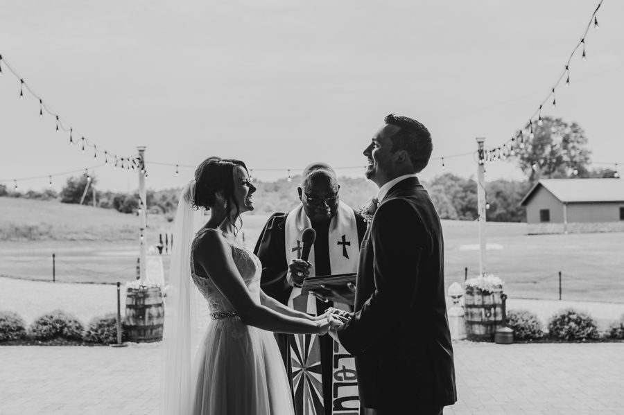 Black and white capture of Cortni and Darren laughing during their wedding ceremony